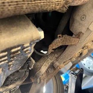 Corroded underside of a car seen from beneath during an inspection